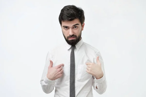 Bonito franzindo a testa homem espanhol com cabelo volumoso e barba apontando os dedos para si mesmo — Fotografia de Stock