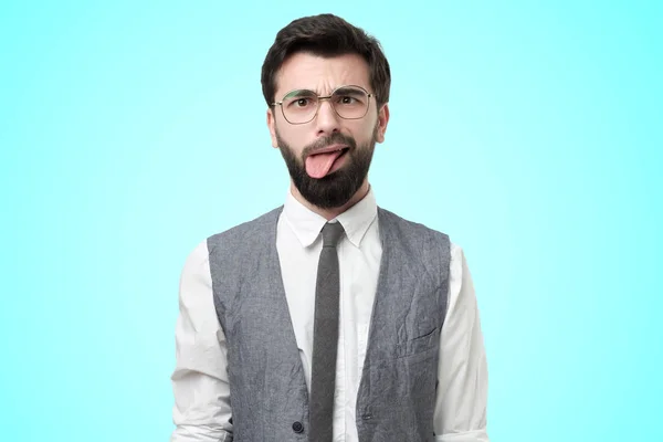 Jonge man draagt een wit shirt en vest voelt zich ontstemd, toont tong — Stockfoto