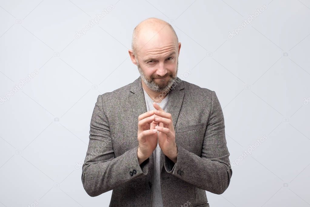 Cunning tricky mature man thinking with hand together over white background. Concept of unfair game