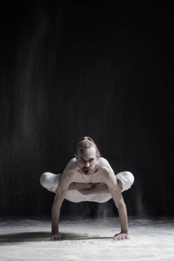 Beyaz delikanlı yoga eğitmeni horoz poz horoz duruş Kukkutasana yapıyor