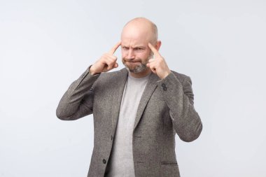 Bir şey hatırlamaya çalışarak Tapınağı karşı parmağıyla işaret kızgın yorgun Avrupa adam. İspanyol sakal yöneticisidir haber ile şaşkın.