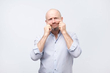 Cilt ve kırışıklıkları sorunları. Beyaz tişörtlü derisi yüz germe yakışıklı beyaz adam. Yüzündeki kilo kaybettikten sonra ilave cilt