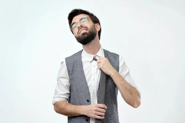 Hispánský mladík ztrácí kravatu na šedém pozadí. Je to pocit, že to nemůže dýchat. — Stock fotografie