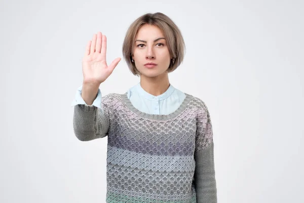 Junge Frau steht mit ausgestreckter Hand und zeigt Stopp-Geste — Stockfoto