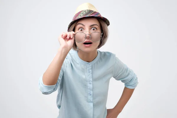 Überraschte junge Frau mit Hut und Brille mit offenem Mund — Stockfoto