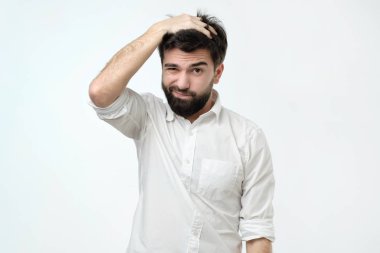 Şaşkın ifade ile seyir sakallı İspanyol adam tırmalamak baş, clueless