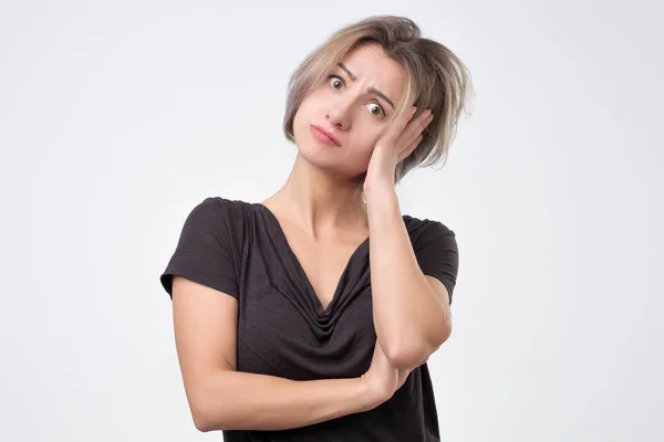 Puzzled female dressed in black t-shirt, being clueless and uncertain. Stock Image