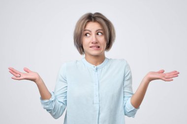 Şüpheli, belirsizlik veya ilgisizlik ifade kadın onun omuzlarında shrugging Mavi giysili
