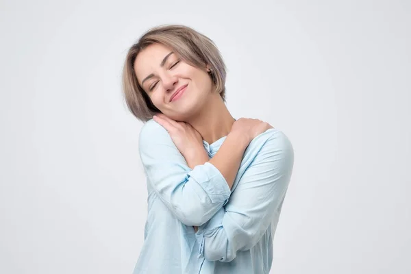 Kaukasische vrouw in blauw shirt knuffelen zichzelf knuffelen. — Stockfoto