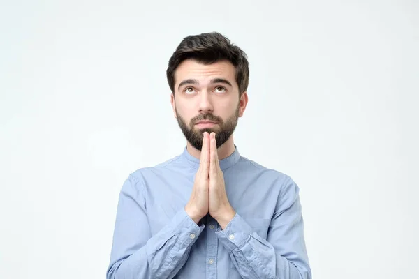 Cara de camisa azul de mãos dadas em oração e olhando para câmera hopefu — Fotografia de Stock