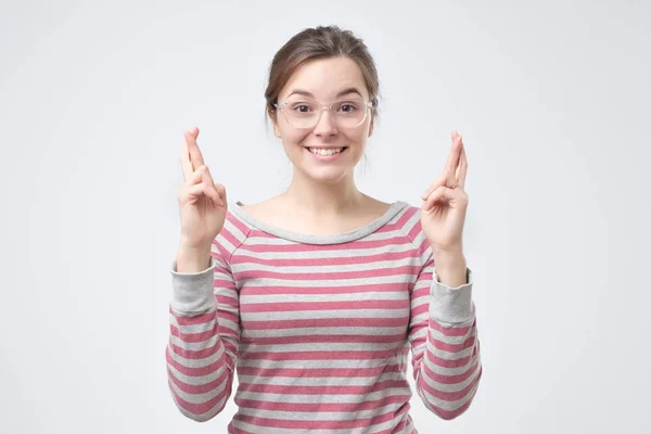 Girl having excited, superstitious and naive look, keeping fingers crossed — Stock Photo, Image