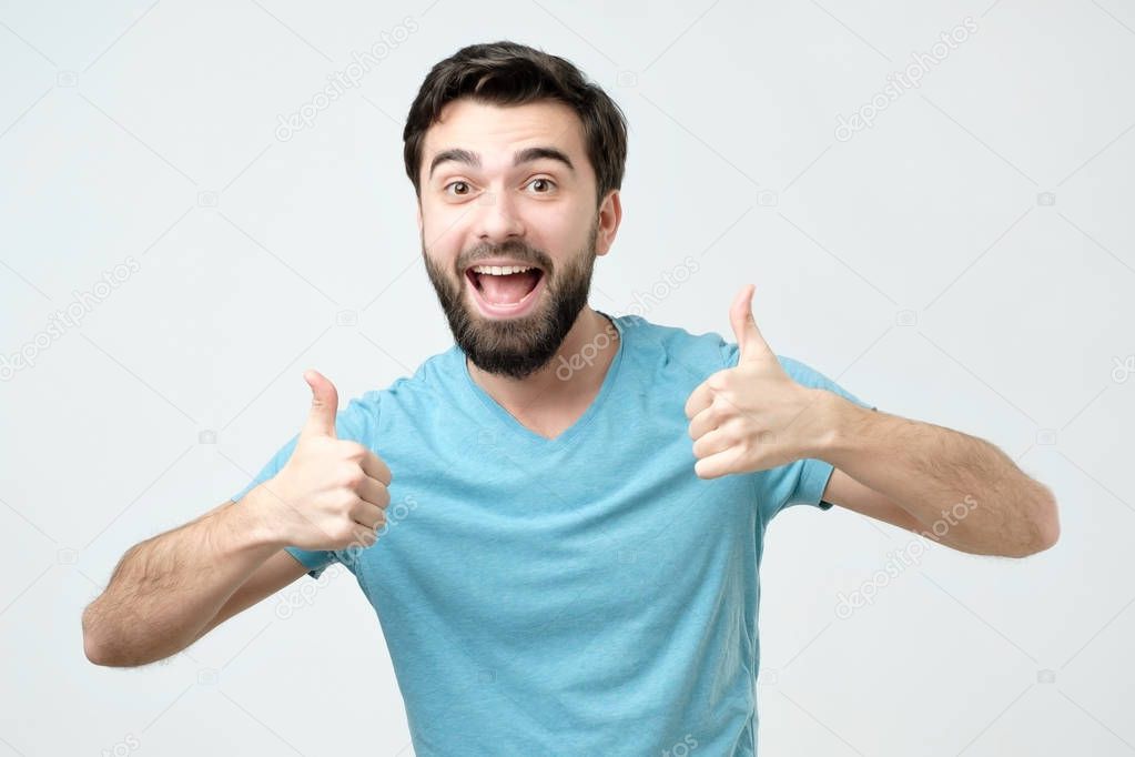 Smiling man showing both thumbs up and looking at camera. Handsome guy advertising something