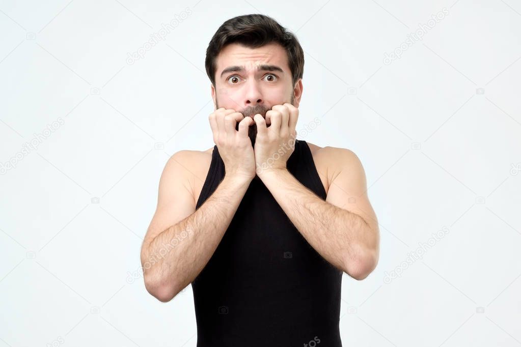 Man covering mouth with hands and round eyes experiencing deep astonishment