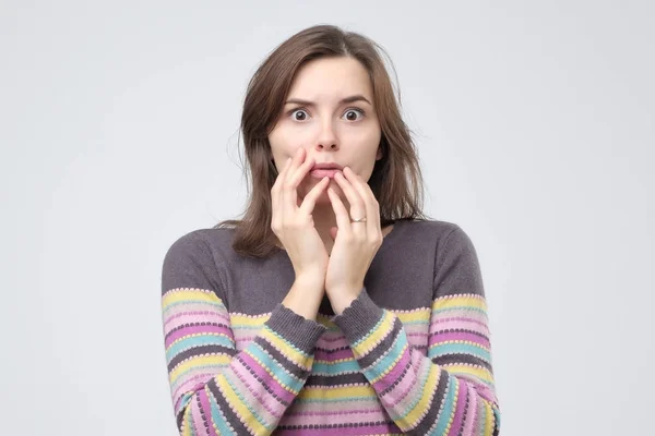 Überraschte Frau hält ihre Hand auf die Wange und öffnet den Mund. — Stockfoto