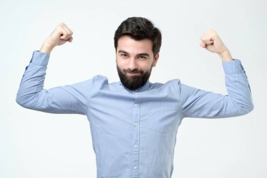 Güçlü adam yumruk, rahat mavi gömlek giymiş clenches, zaferini kutluyor