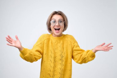 Sarı kazak bağırarak büyük haberle şok sürpriz genç kadın. Kameraya olumlu yüz duygu ile seyir.