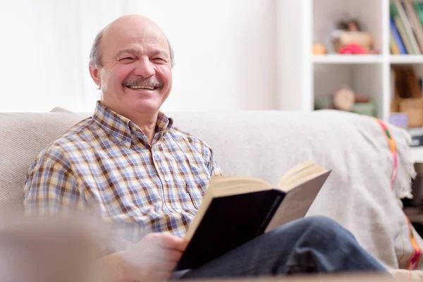 Senior Man Lezen Van Een Boek Glimlachend Kijken Camera Zit — Stockfoto