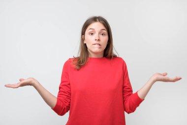 Clueless şaşkın kadın ile kırmızı kazaklı yaygın olarak belirsizlik ifade omuzlarını shrugging tereddüt sahip gözlerini açtı. Bu konuda kimsenin umurunda değil