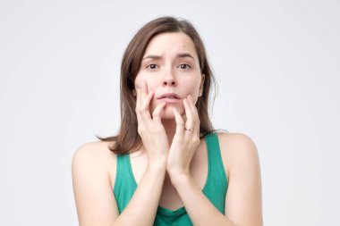 Genç kadın, korkuyor ve endişeli parmak tırnaklarını ısırma gri bir arka plan üzerinde izole geniş açılmış gözlerle kameraya bakarak korkuttu. Negatif insan duyguları