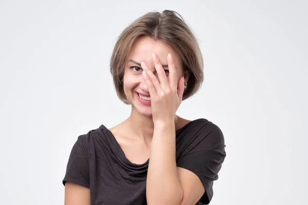 Игривая женщина с улыбкой подглядывает между пальцами — стоковое фото
