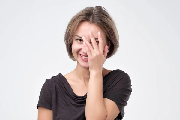 Playful woman peering between her fingers with a smile — Stock Photo, Image