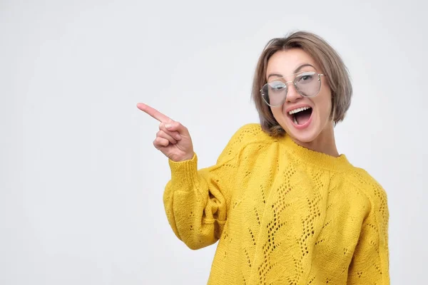 Fiatal európai lány sárga pulóver ujját felfelé mutató. — Stock Fotó
