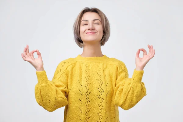 Mosolygó fiatal nő sárga pulóver, meditáció, jóga gesztus kézen — Stock Fotó
