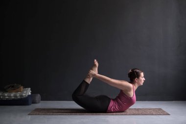 Genç kadın pratik yoga yay poz, Dhanurasana.