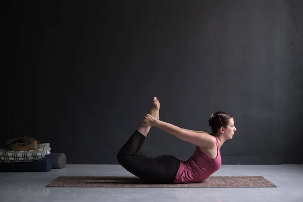 Mujer joven practicando yoga pose de arco, Dhanurasana . — Foto de Stock