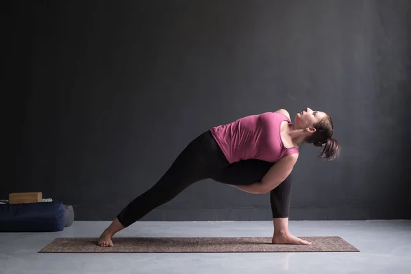 Женщина практикует йогу Utthita parsvakonasana упражнения, расширенный угол позы — стоковое фото