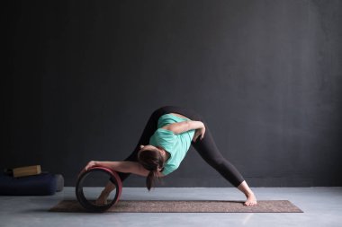 Kadının yoga asana bacaklı İleri Bend geniş yapması özel tekerleğini kullanarak.