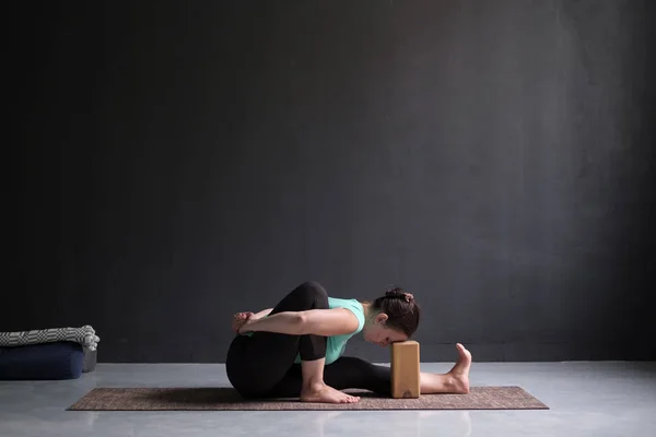 Mujer joven practicando yoga asana amarichyasana en interiores — Foto de Stock