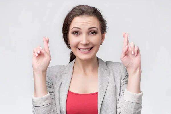 Happy lovely young woman keeps fingers crossed wishing for good luck — Stock Photo, Image