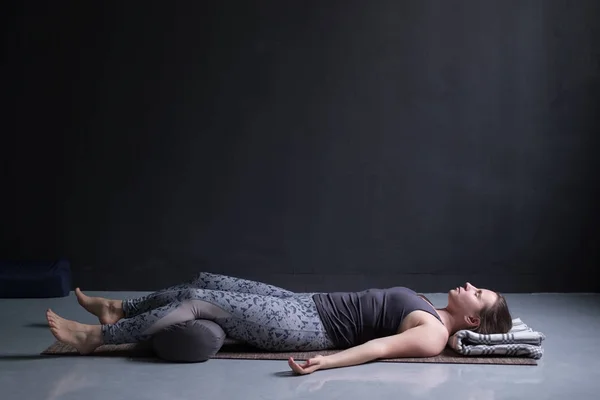 Vrouw uit te werken, doen yoga oefening op houten vloer, liggend in de Shavasana — Stockfoto