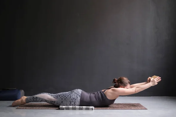 Mujer practicando yoga, estirándose en el ejercicio de Salabhasana, pose de patadas dobles —  Fotos de Stock