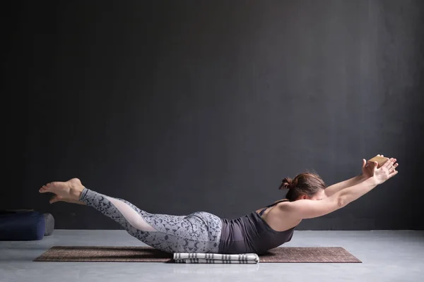 Mujer practicando yoga, estirándose en el ejercicio de Salabhasana, pose de patadas dobles —  Fotos de Stock