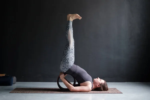 Mujer joven practicando yoga, de pie en Viparita Karani ejercicio, usando rueda — Foto de Stock