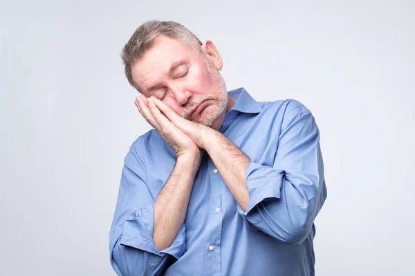 Europäischer Mann im blauen Hemd schläft müde auf Händen. — Stockfoto