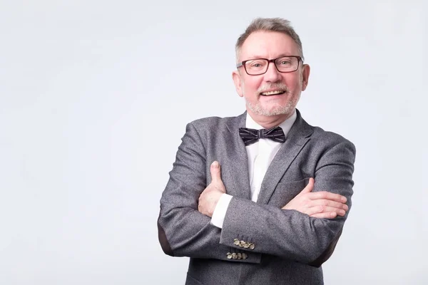 Hombre de negocios senior en traje y pajarita posando con los brazos cruzados — Foto de Stock