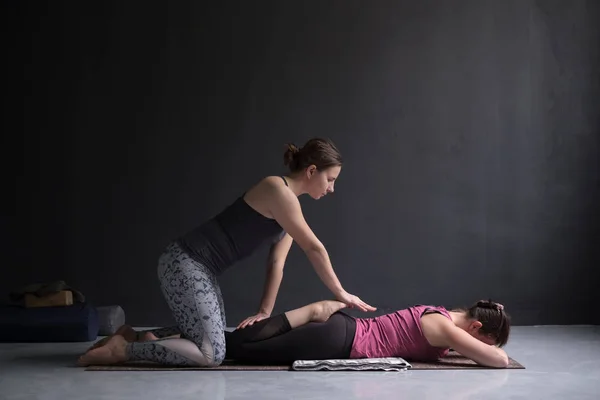 Treinador ajudando mulher praticando ioga, fazendo exercício Bhekasana juntos — Fotografia de Stock