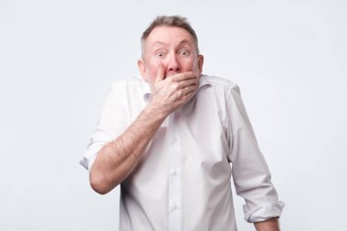 el ile ağız kapsayan ve kameraya bakarak Beyaz tişörtlü adam