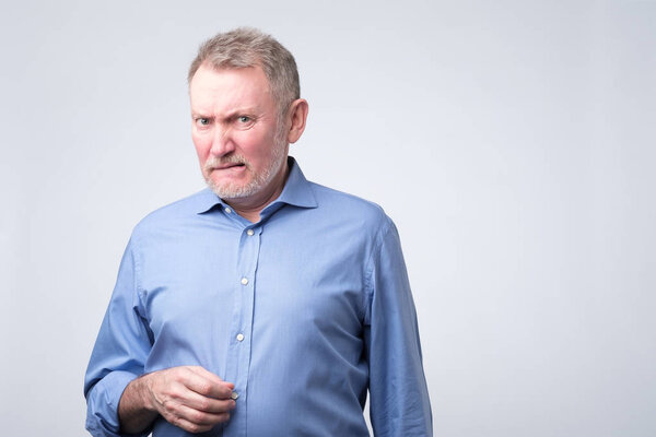 Senior man in blue shirt looking with disbelief expression .