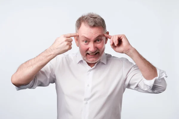 Boos senior man gebaren met zijn vinger tegen de tempel vragen bent u gek — Stockfoto