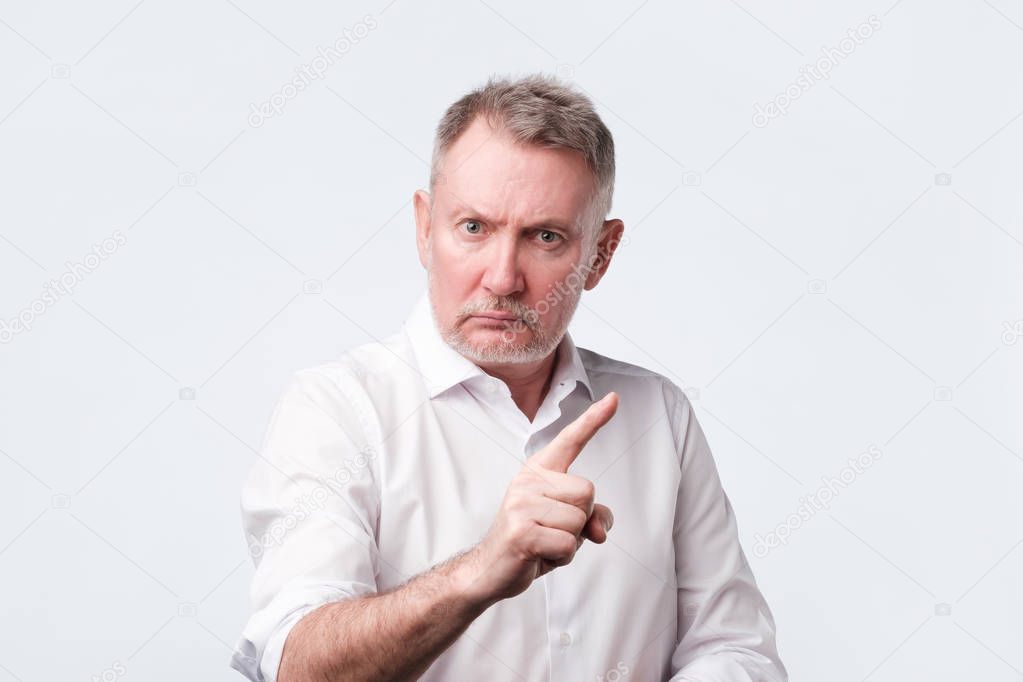 Strict senior man showing index fingers up, giving advice