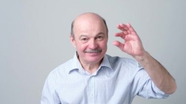 Bir şey figers ile küçük gösterilen bıyıklı üst düzey beyaz kel adam.