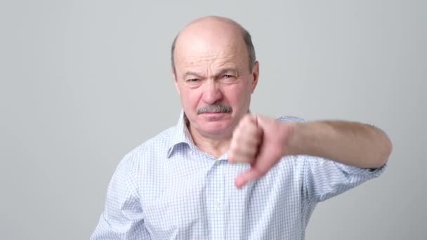 Mature caucasian man showing his dislike and disappointment with thumbs down — Stock Video