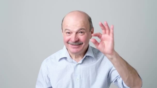 Senior man with mustache showing something small with figers. — Stock Video