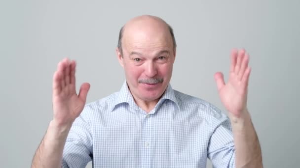 Зрелый мужчина жестикулирует руками, показывая знак большого и большого размера, символ меры . — стоковое видео