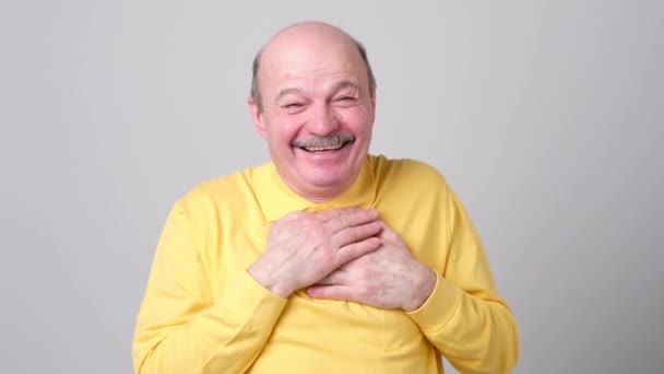 Glücklicher älterer Mann hält Palme am Herzen und lächelt dankbar und nimmt Kompliment entgegen — Stockvideo