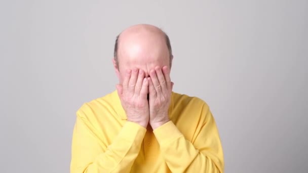 Мужчина в жёлтой рубашке закрыл лицо руками . — стоковое видео